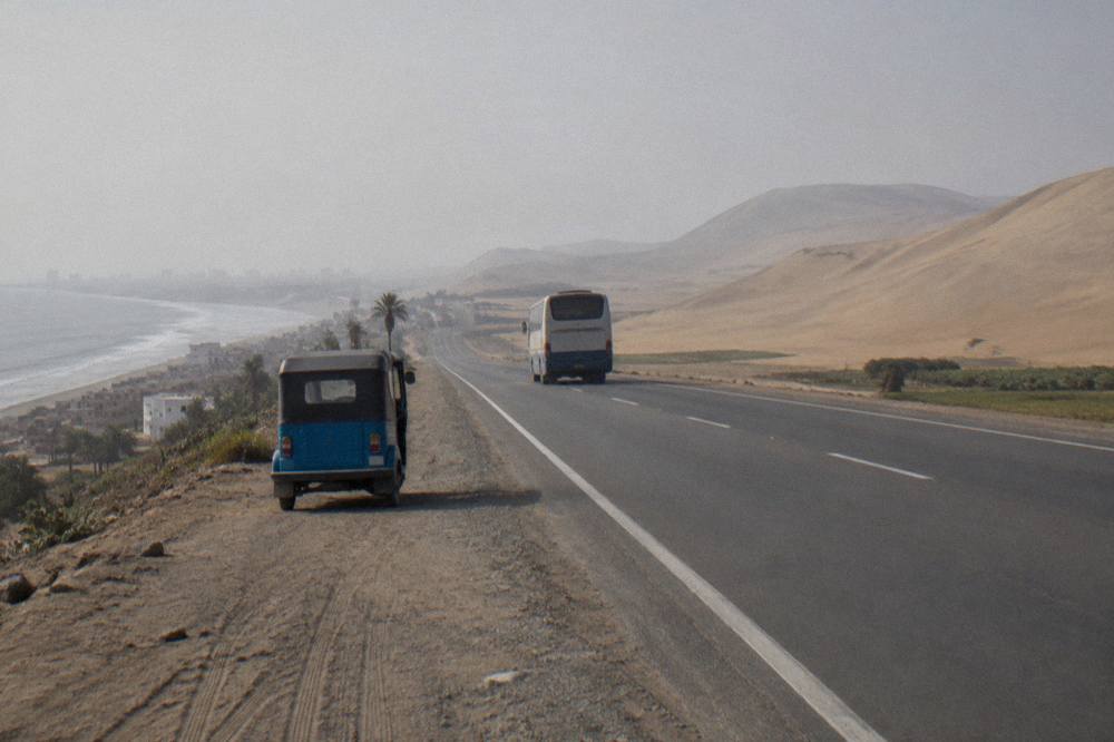 A bus traveling a high desert road toward Lake Titicaca with wide open sky
