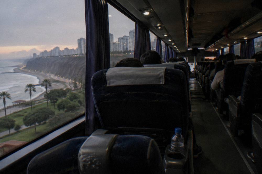 Interior of a long-distance coach with rows of wide reclining seats and overhead luggage racks