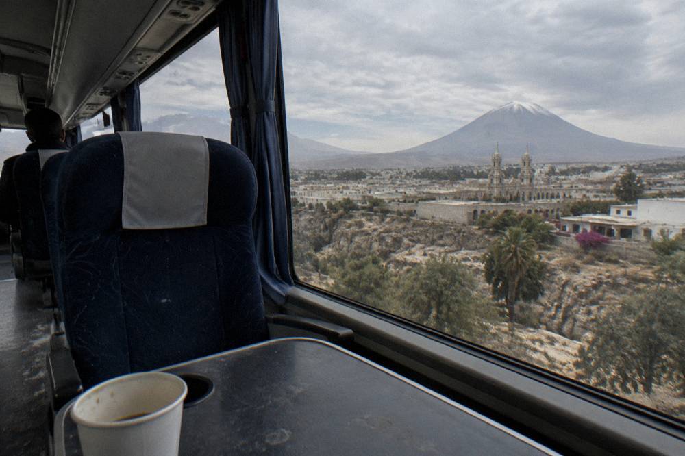 Interior of a long-distance coach with wide windows and reclining seats facing a mountain view