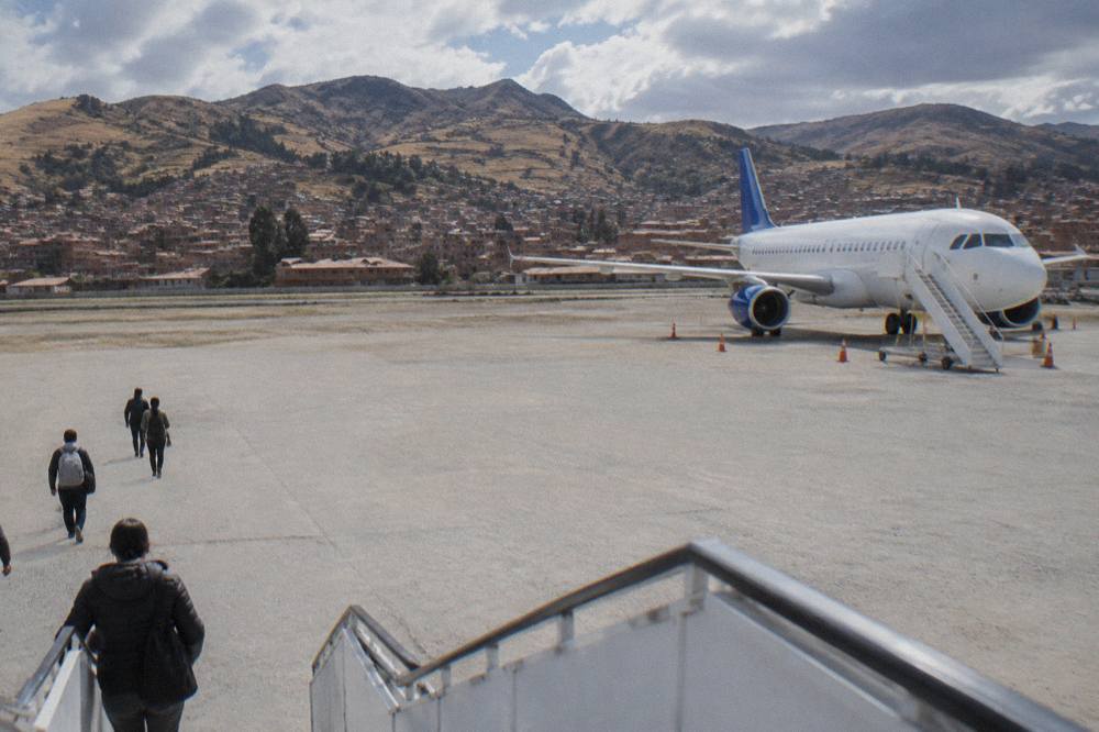 The tarmac and terminal buildings of Cusco airport with dry Andean hills rising behind them