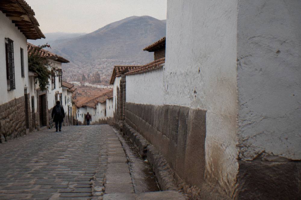 Old stone alleyway with whitewashed walls and a mountain rising behind the city