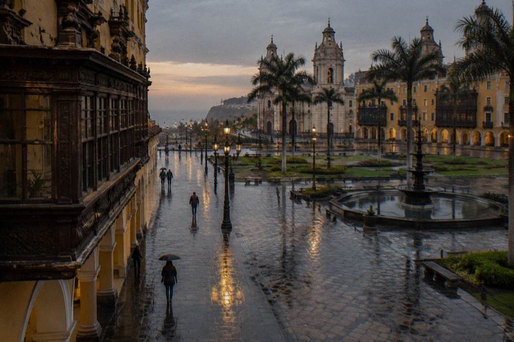 Wooden colonial balconies above a wide plaza with fountains in Lima's historic center