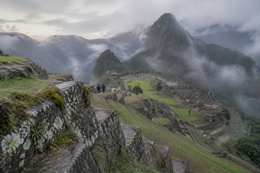 Stone terraces of Machu Picchu under morning light with green peaks behind