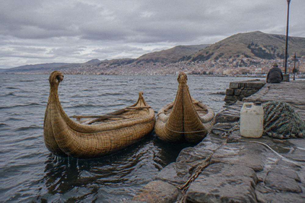 Reed boats floating on the blue expanse of Lake Titicaca at midday