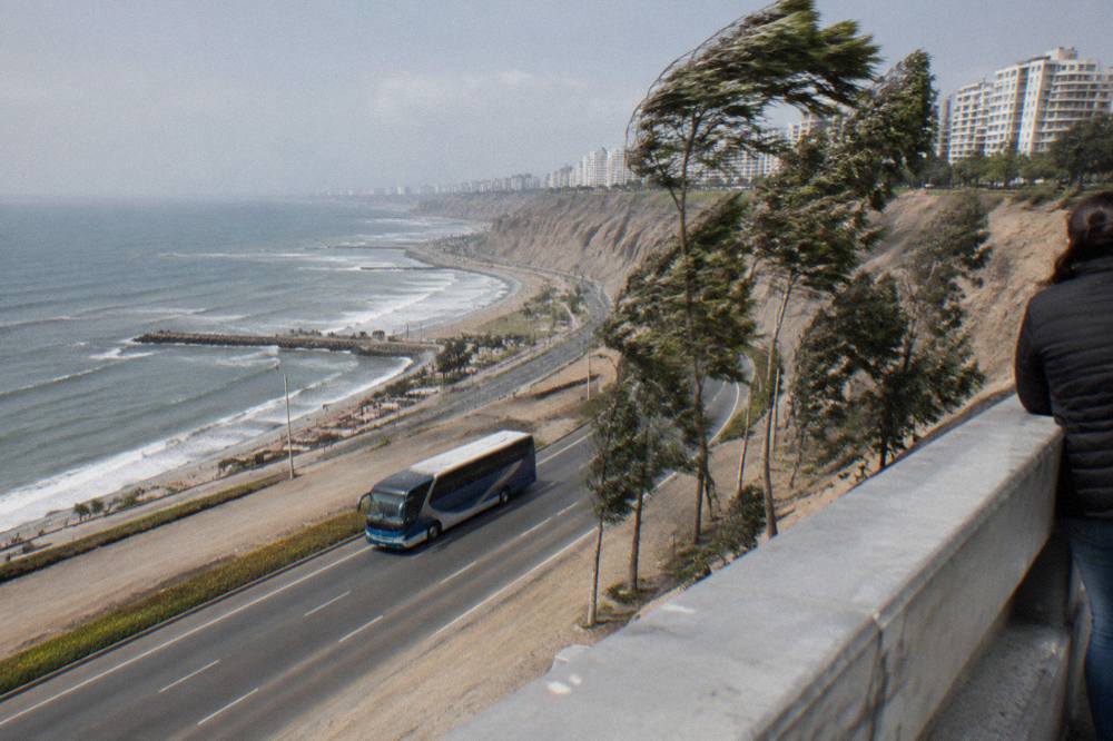 A tour bus traveling along a coastal highway with ocean cliffs on one side