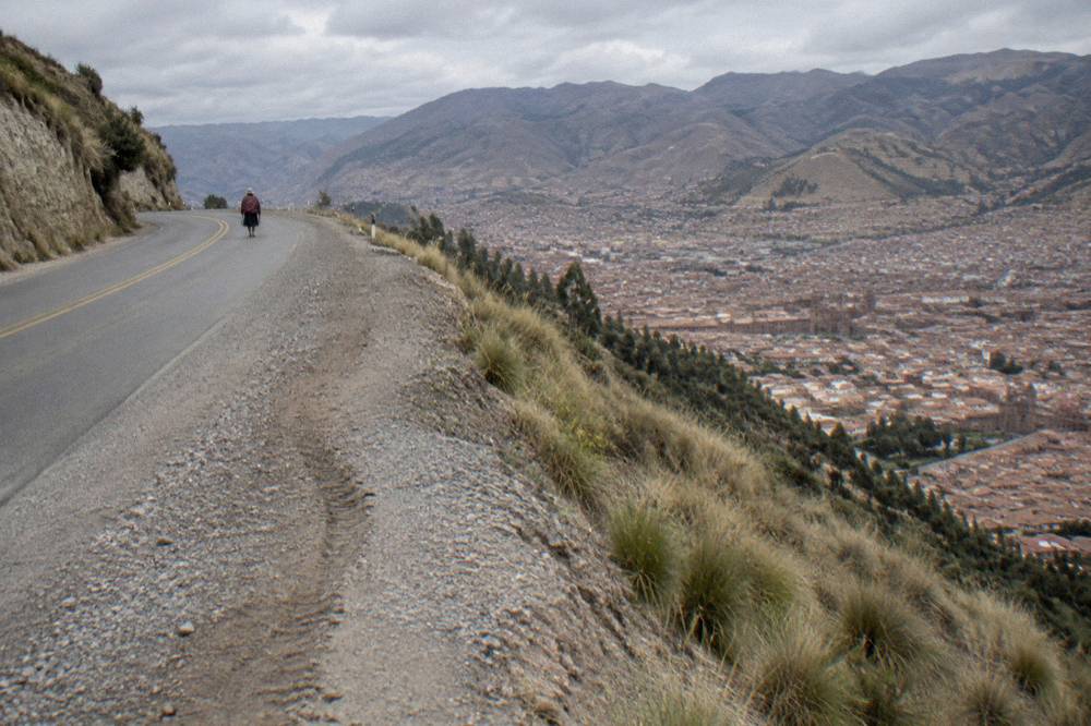A two-lane mountain road curving along a hillside with a steep drop to one side