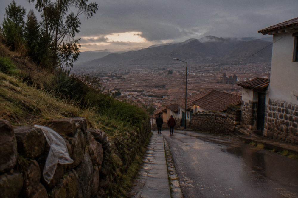 A paved road descending through brown Andean hills toward a wide valley with distant peaks