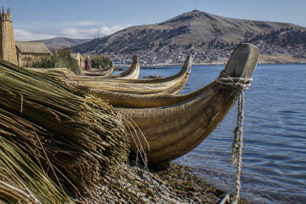 Reed boats on a high-altitude lake with brown hills behind