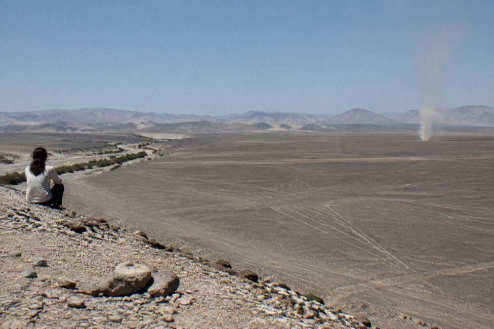 Small single-engine aircraft banking over pale desert plains under a clear morning sky