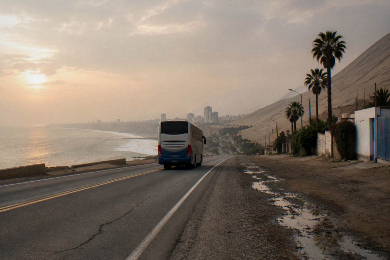 A modern touring bus on a coastal desert highway in Peru with ocean haze on the horizon