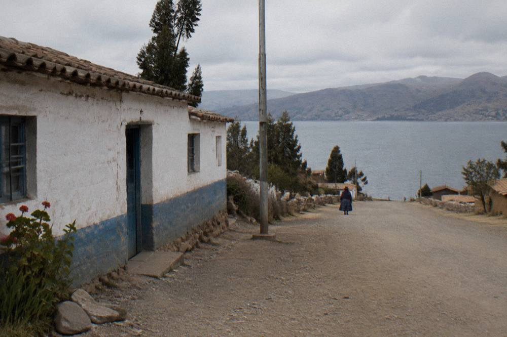 A low border building beside an empty high-altitude road with mountains in the distance