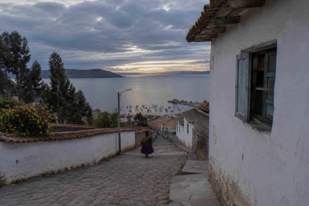 A quiet lakeside town street with white buildings under a wide sky at dusk