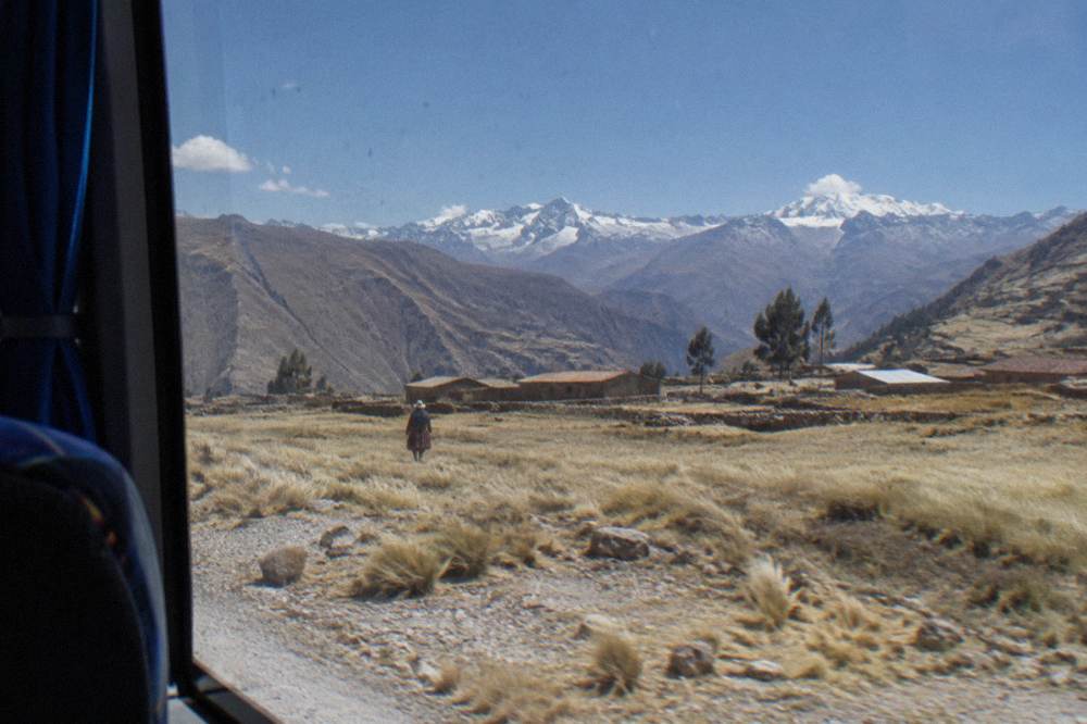 A window view from a bus crossing a high open plain with distant snow peaks