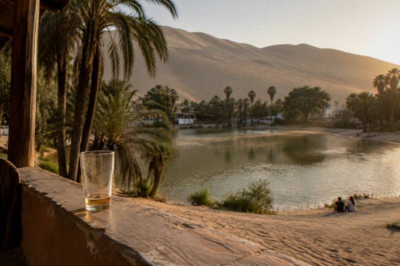 Golden desert dunes rising behind the lagoon at Huacachina, an oasis stop on the coastal route south of Lima