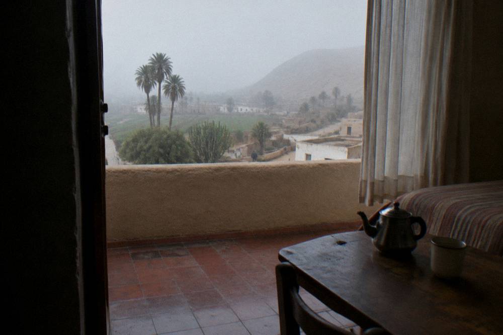 A calm hotel room in a highland town with a teapot on the table and morning light