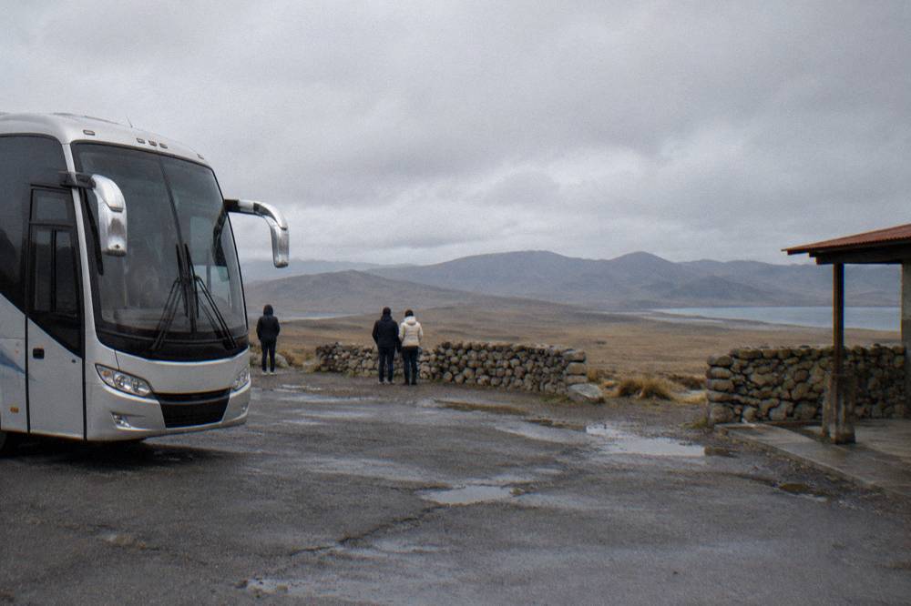 Modern touring coach parked at a high plain rest stop with wide open scenery beyond