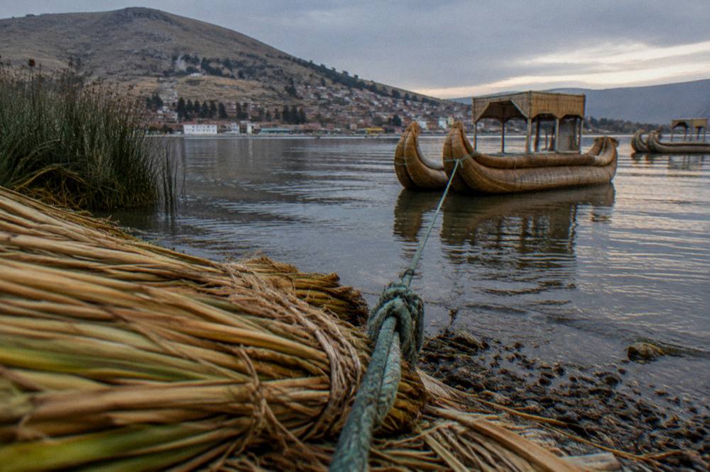 Reed boats moored on a calm lake shore at high altitude with muted evening light