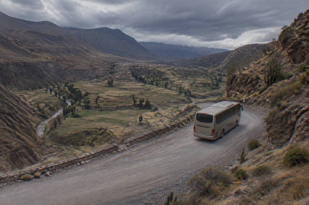 Tourist bus traveling on a mountain road above a high Andean plain