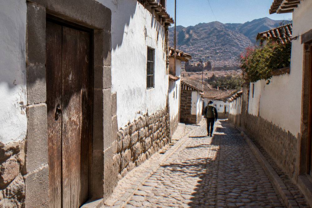 Backpacker walking with a pack through a high Andean village street