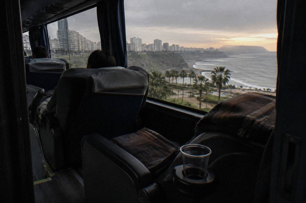 Interior of a long-distance tourist bus with wide reclining seats, blankets on the seats and large windows