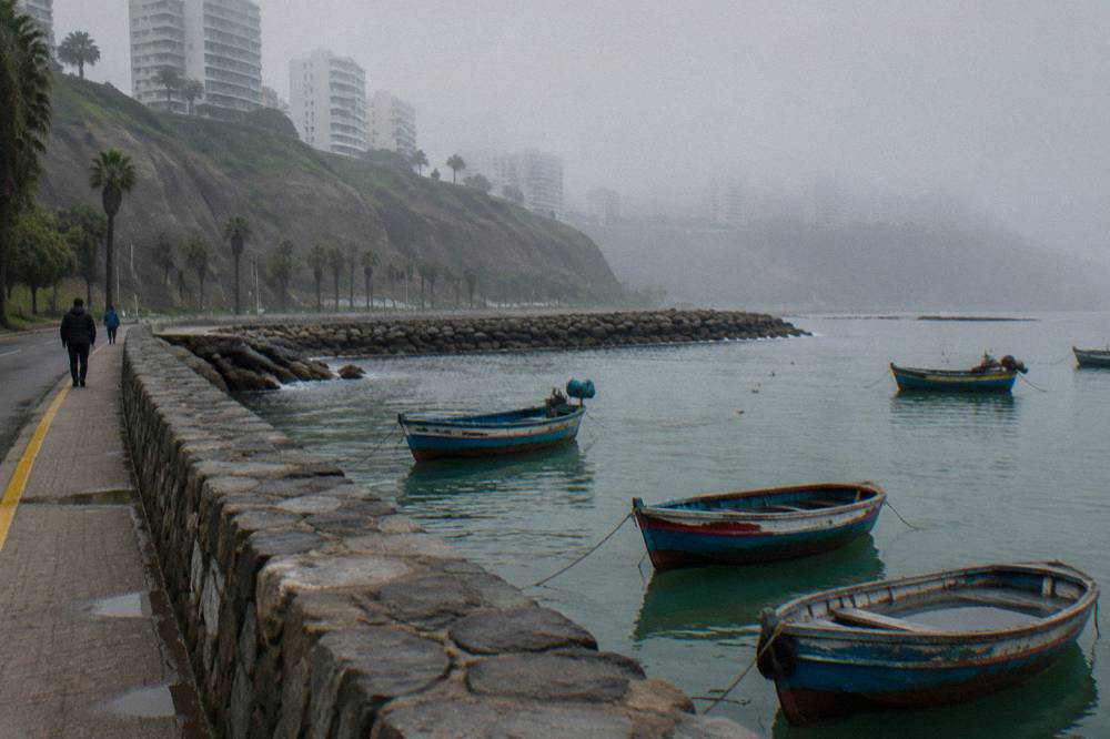 Quiet lakeshore road in Copacabana, Bolivia with small stone buildings and moored boats on calm water