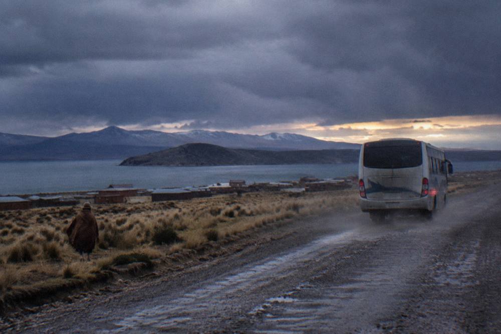 Tourist bus traveling across the open altiplano grassland toward Puno