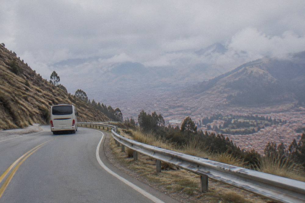 Tourist bus traveling on a two-lane mountain road above a high Andean plain