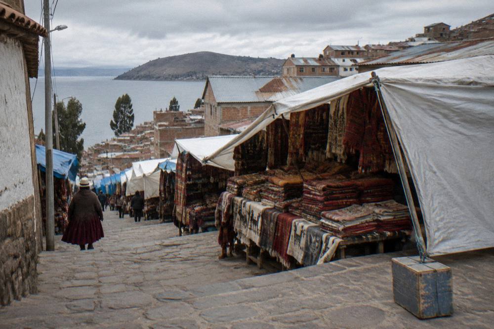 Market stalls with woven textiles on a highland town street near the lake