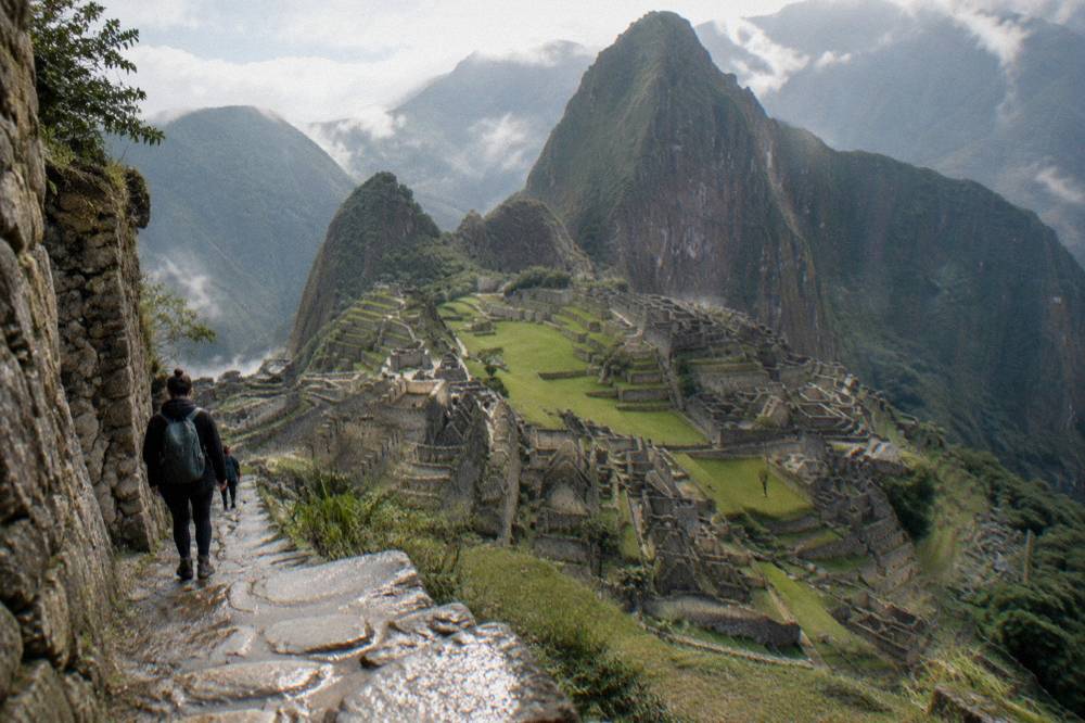 The terraced mountainside of Machu Picchu citadel under morning light with green peaks behind