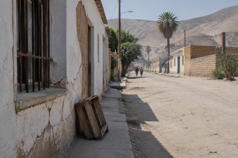 Small desert town at the foot of barren hills under a wide pale sky