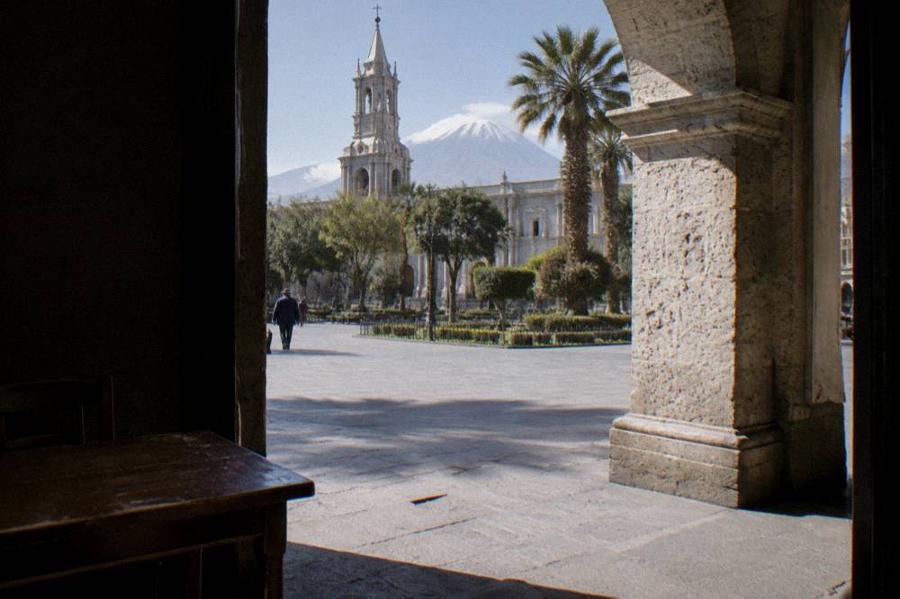 Colonial stone archway and quiet plaza under a bright highland sky