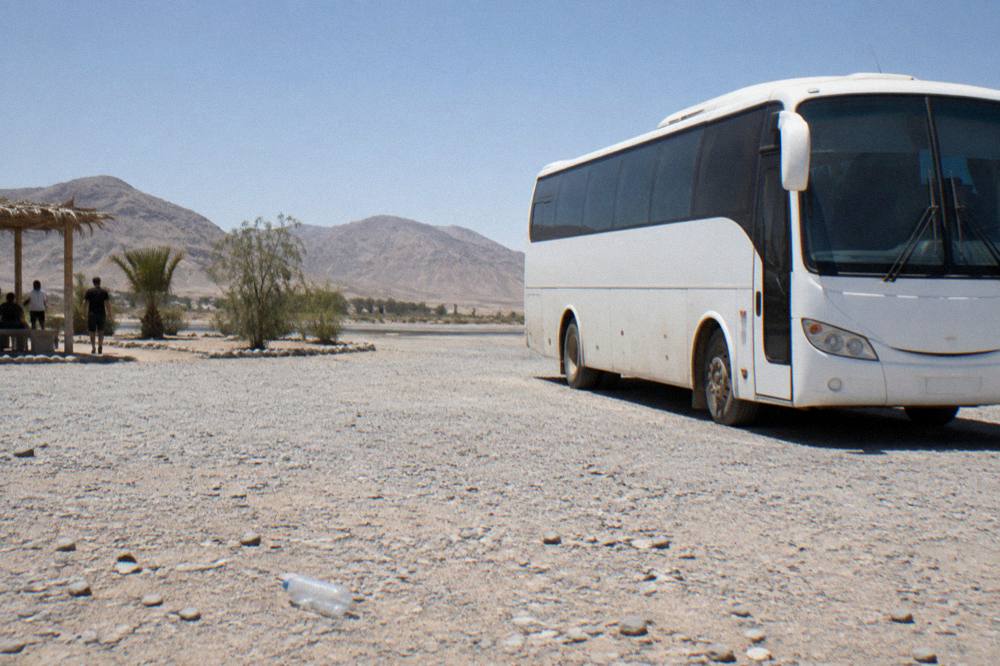 Modern touring bus parked at a desert rest stop under a clear sky