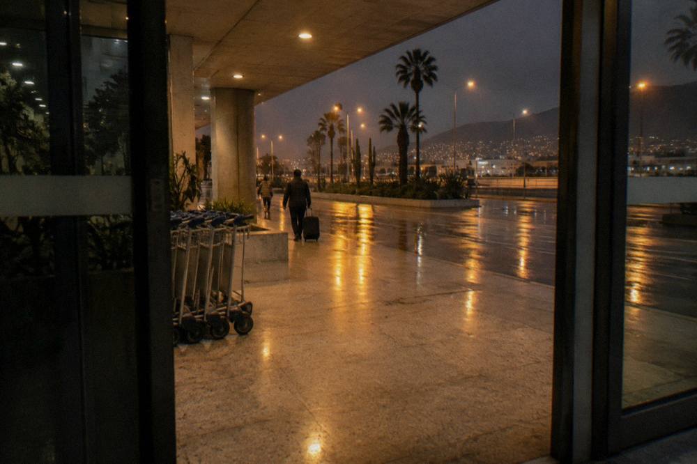 An airport arrivals hall with sliding doors and covered walkways outside