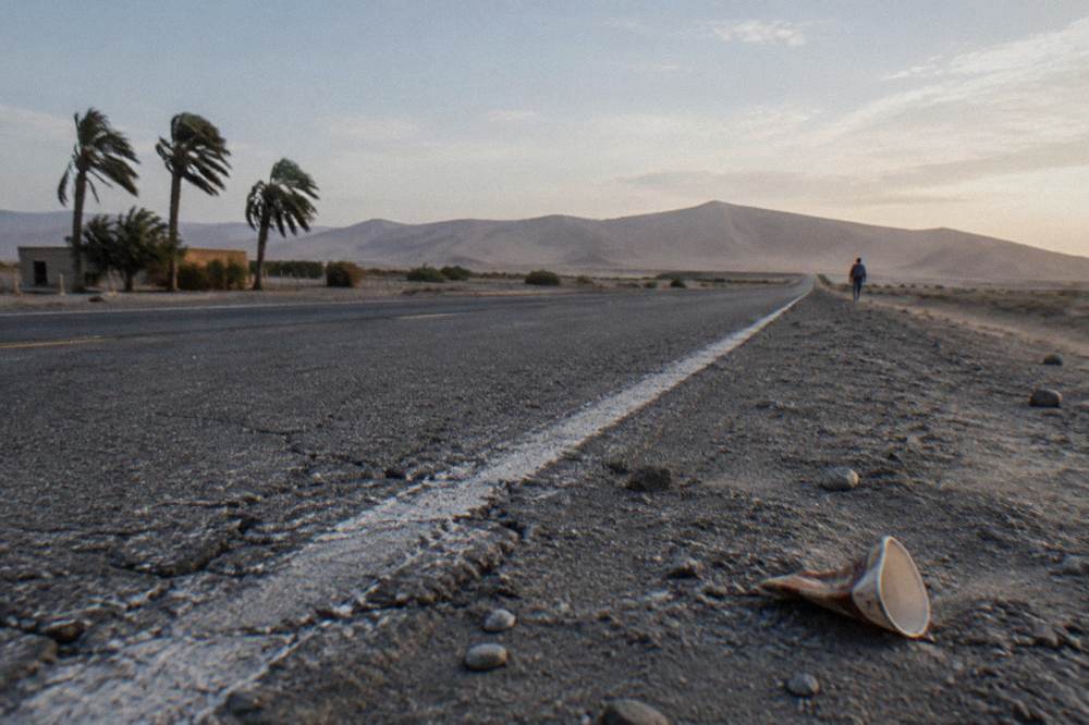 A paved two-lane highway crossing open coastal desert under a wide sky