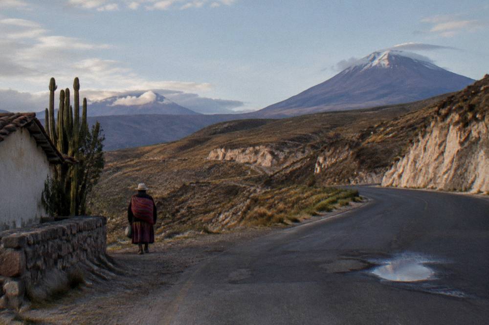 A paved mountain road climbing through treeless brown highlands toward a high pass