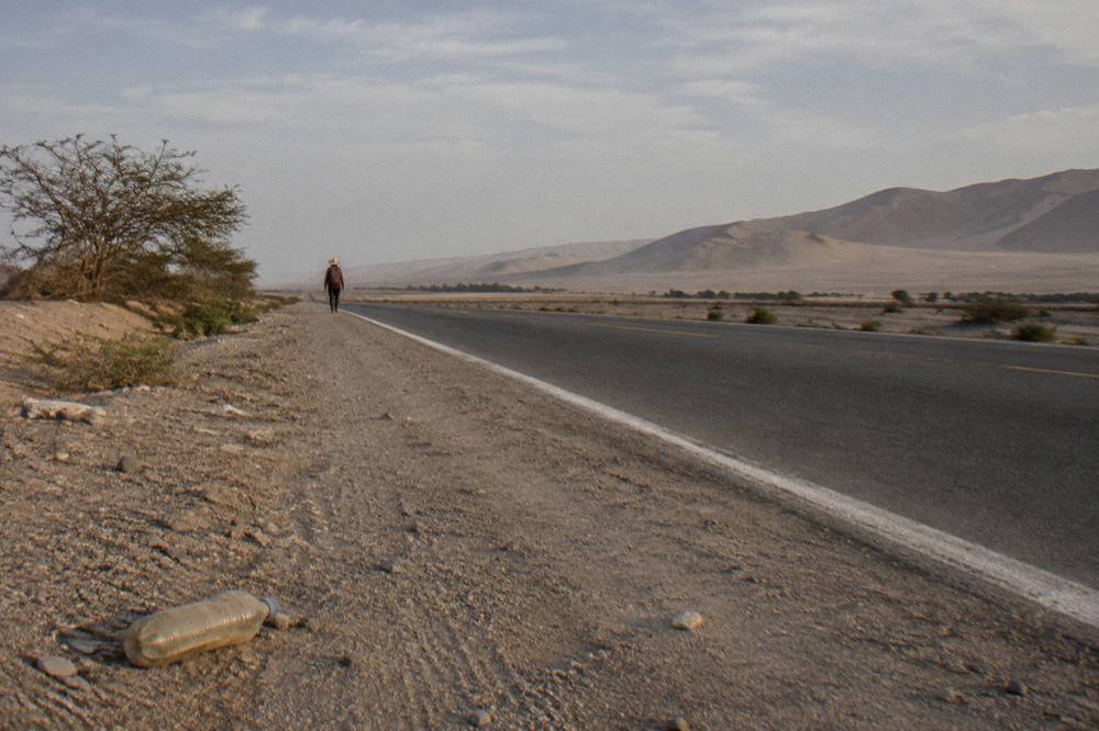 A long desert highway cutting through flat coastal sand toward distant dunes