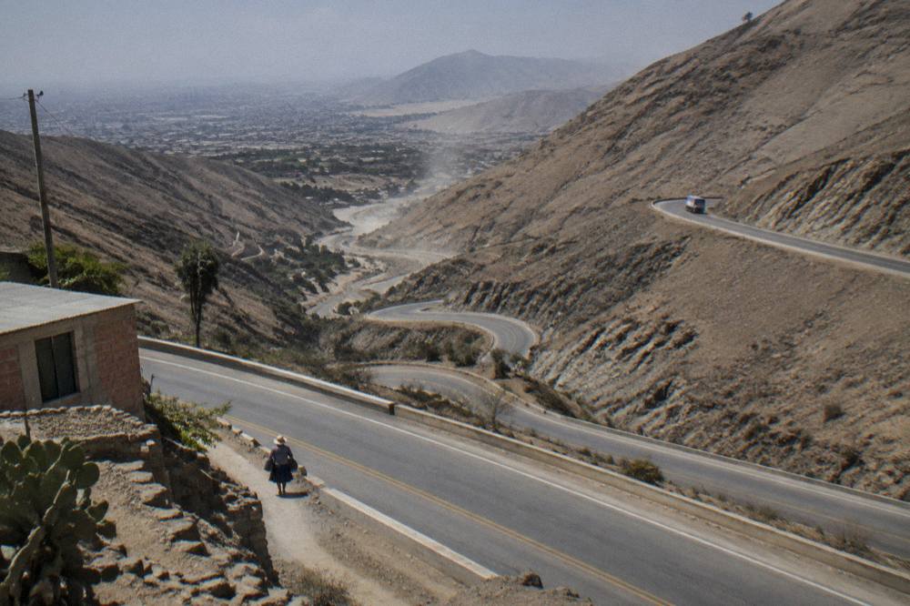 Highway climbing through dry brown mountains with switchbacks visible on the far slope