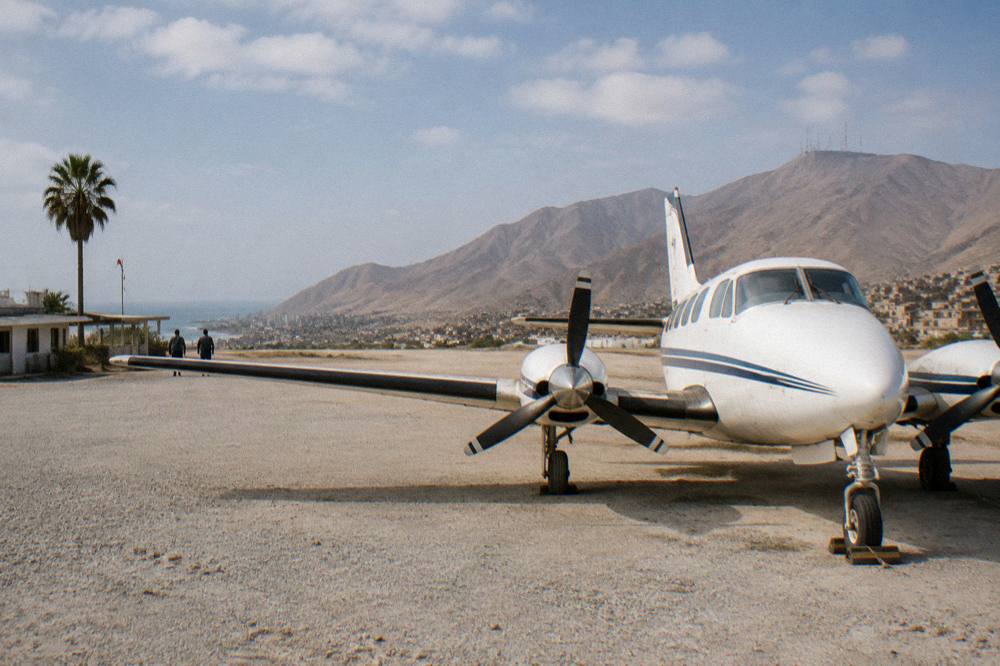 Small twin engine aircraft parked at a high altitude regional airfield with dry mountains behind