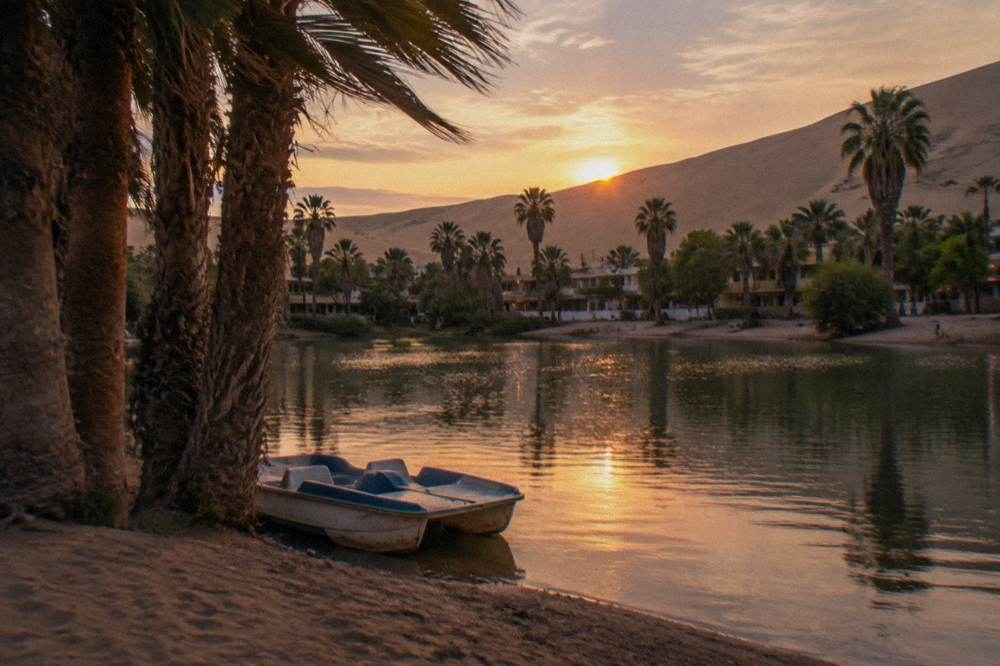 Sunset light over the Huacachina oasis lagoon surrounded by tall sand dunes