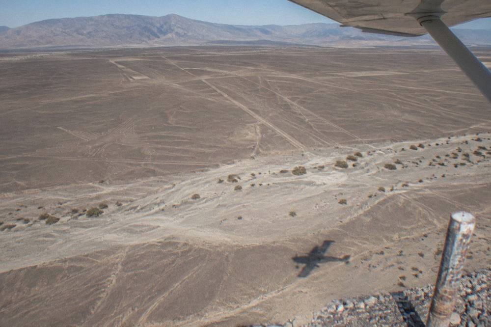 Light aircraft banking over the geometric lines etched into the Nazca desert plain