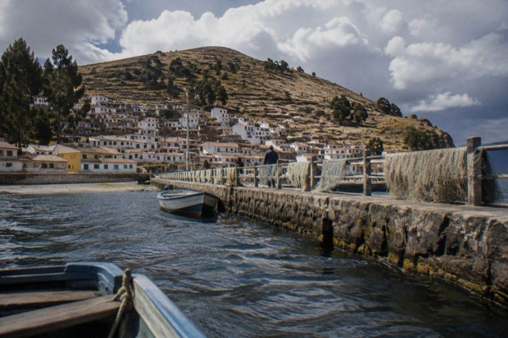 Small Bolivian town on the shore of a vast high-altitude lake with boats at a stone pier