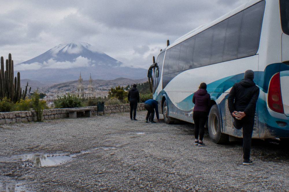 Interstate-style long distance tourist bus parked at a mountain rest stop with passengers stretching