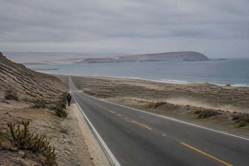 Empty Pan-American Highway cutting through barren desert hills on the Peruvian coast