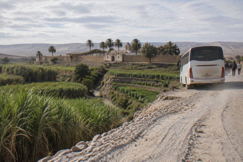 Tourist bus parked on a mountain road above a canyon with terraced fields below