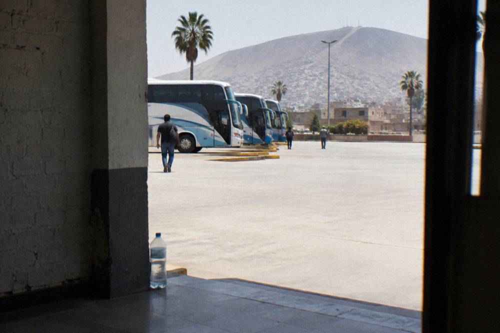 Bus terminal platform with coaches waiting under bright morning light