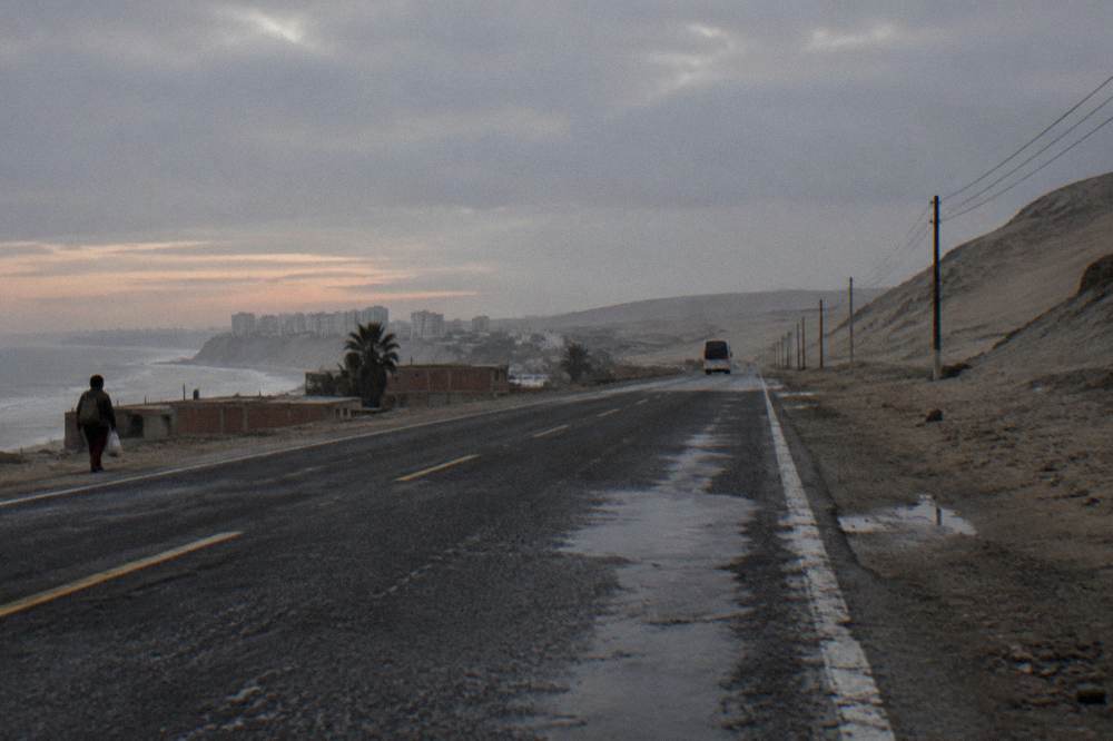 Bus traveling on a straight desert highway at dusk