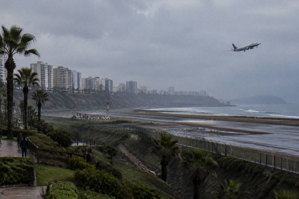 Airliner climbing away from a coastal airport with the sea below