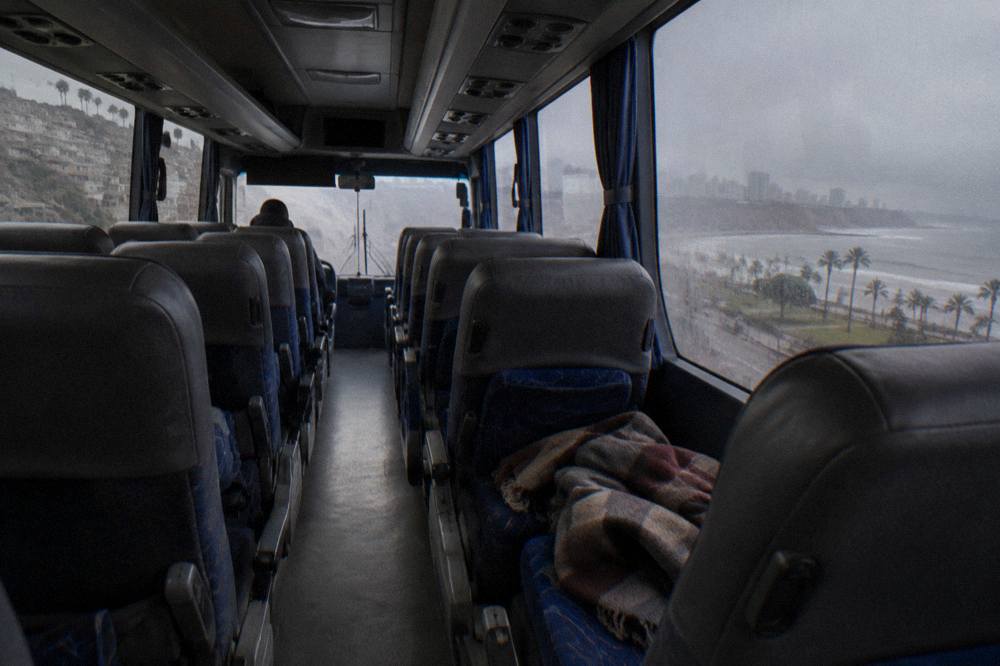 Interior of an empty long-distance coach with rows of wide reclining seats and reading lights