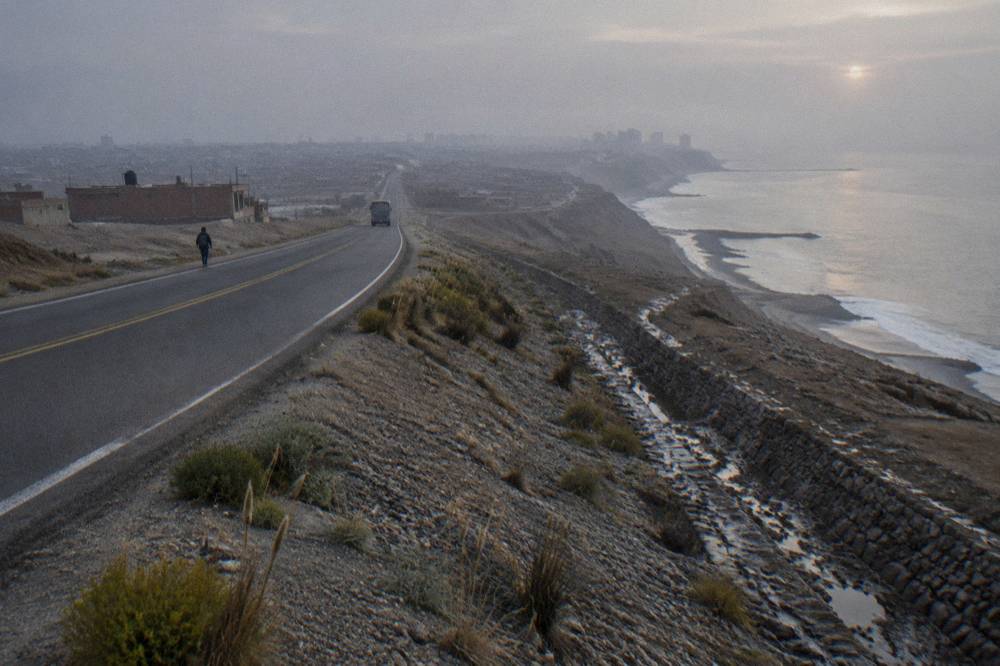 A misty Andean altiplano landscape at dawn with a two-lane road running toward the horizon