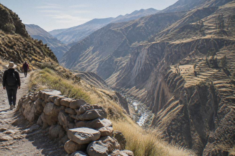 Terraced canyon walls under bright morning sky with a river far below
